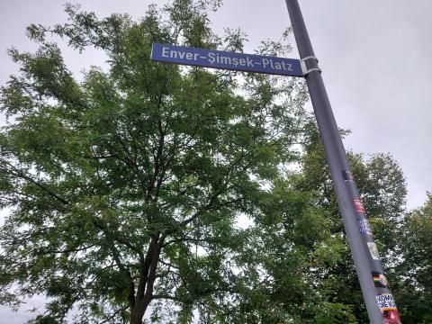 Straßenschild Enver-Şimşek-Platz vor Bäumen